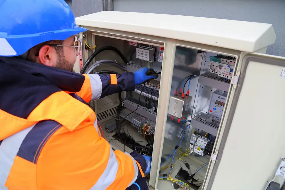 Electrician in hi-vis working on a commercial distribution board