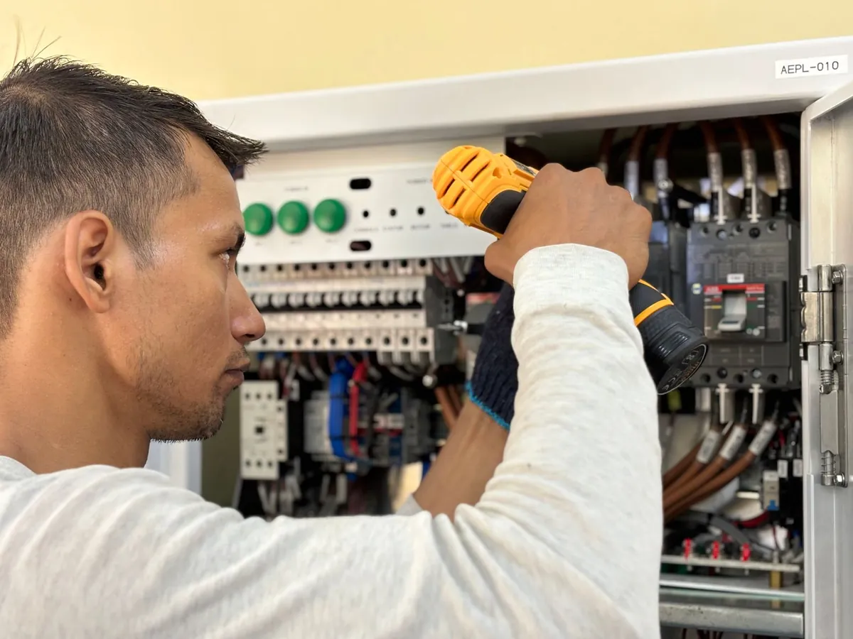Electrician using a drill on a switchboard during an upgrade